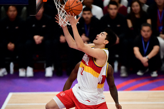 NBA 篮球比赛现场，球员在篮下争抢，场馆内观众席坐满球迷